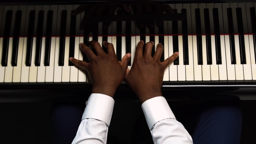 Top view of male hands playing the grand piano. The African American touches the black and white keys with his fingers to create the rhythm of the melody. Close up black hands of a male pianist. Royalty-Free Stock Footage #1069225993