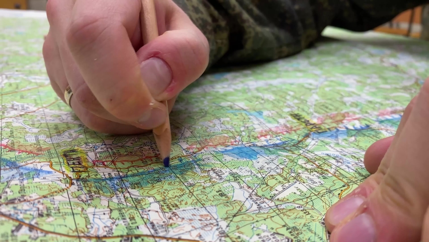 the soldier looks makes marks on the map with a pencil extreme close up