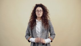 The desperate young woman, with her hands clasped, asks for help and insists strongly on helping her. Cretaceous in gray jacket and white shirt, with glasses posing isolated on a beige background in
