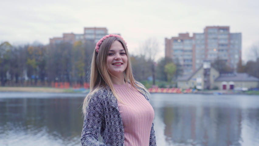 Girl posing in the autumn evening against the backdrop of a city lake.