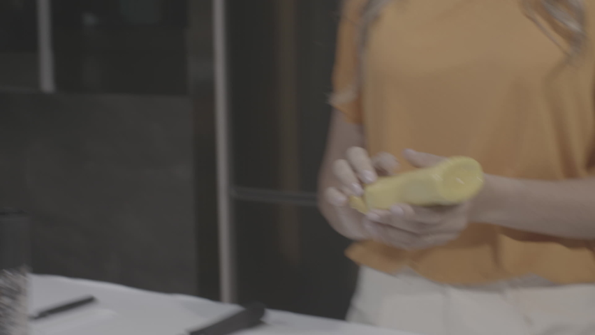 Woman pouring mustard on an Arabic bread from the bottle