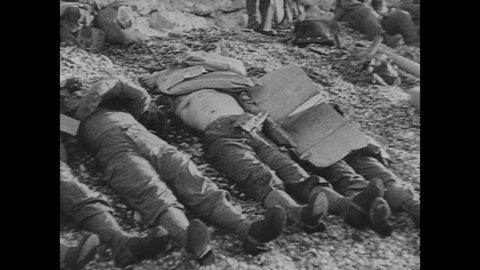 1940s: Dead bodies of soldiers on ground, soldiers sit nearby. . Ship on fire. Navy ship and dead bodies on shore. Medics attend to wounded. Navy ships. Troops rush beach