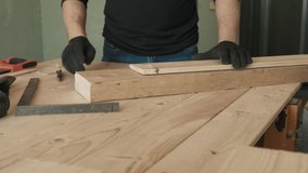 A male construction worker measures the angle with a construction tool and writes with a pen. Close-up without a face. A man in black gloves. 4k video.