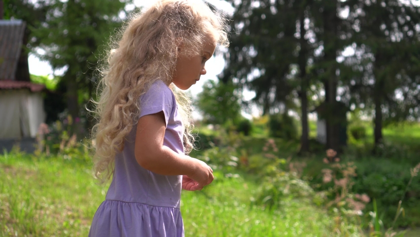 Playful 5 years old child girl throw cones into pond. Preschooler girl in park