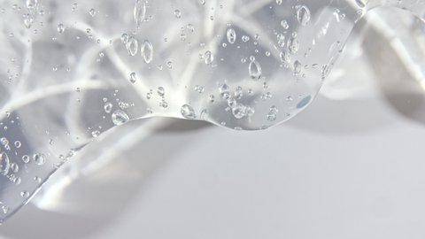 Transparent cosmetic gel fluid with bubbles flowing down on a white surface. Macro Shot 