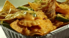 Cheese melting over tortilla chips with jalapenos