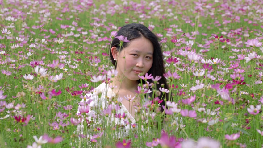 slow motion beautiful woman with dress and put on hat in flower garden 