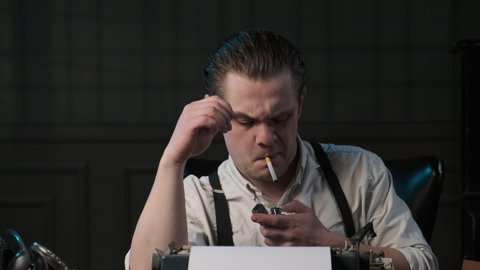 Detective or gangster sits at table in retro interior and talks on phone. mafia boss from the 1920s is very angry and shouts into tube. Trying to light cigarette.