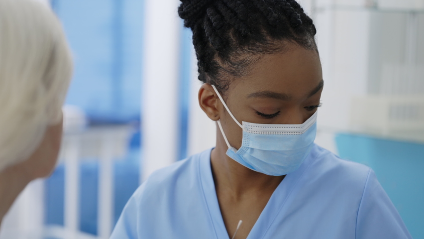 Crop view of medical female worker in protective mask and gloves taking PCR test sample from elederly patient in hospital room. Concept of Covid reaesearch and diagnostic. Royalty-Free Stock Footage #1069267885
