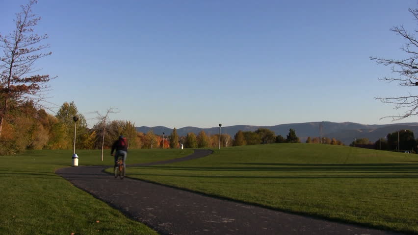A bicyclist rides along a trail in a park.