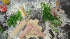Children's hands trying to knead the dough on a cutting table, top of the view, process preparation homemade pizza. 