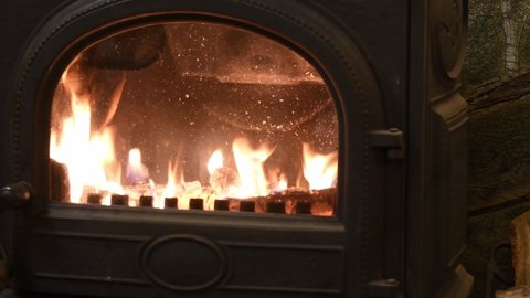 Blazing fire in vintage cast iron potbelly stove with semicircular door. Flame in antique fireplace of retro style interior. Cozy winter background