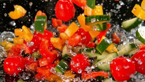 Super Slow Motion Shot of Colorful Vegetables Falling into Water on Black Background at 1000fps.