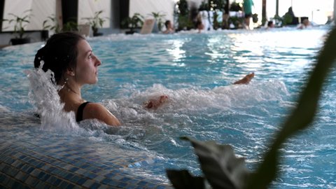 Beautiful girl getting spa treatments in the pool. Beautiful woman having hydrotherapy in the pool at a luxury spa. Hydromassage in the pool. Luxurious spa complex.