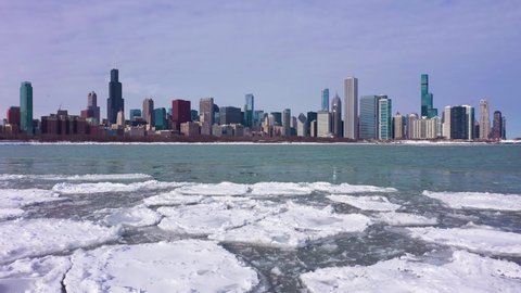 Urban Skyline of Chicago Loop and Frozen Lake Michigan with Ice Lumps on Winter Frosty Day. Aerial View. United States of America. Drone Flies Sideways. Slider Low Level Shot