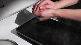 This video shows anonymous chef hand balling up burger meat patties over a stove top cooking area.