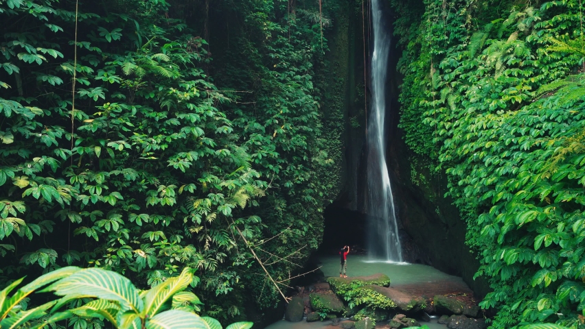 Active lifestyle travel woman practice yoga and balances in nature on background beautiful waterfall hidden in tropical rainforest jungle. 4K Cinematic shot | Shutterstock HD Video #1069291345