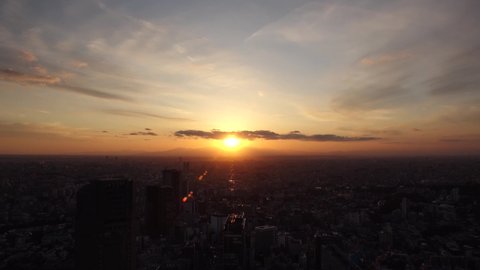 TOKYO, JAPAN : Aerial sunrise CITYSCAPE of TOKYO and MOUNT FUJI. View of rising sun and buildings around Shibuya. Japanese city life and nature concept. Time lapse zoom out video, night to morning.