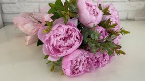 A delicate spring bouquet of pink peonies Sarah Bernhardt and eucalyptus bandaged with ribbons. Close-up flower bots in smooth video shooting. Romantic gift to your beloved girl