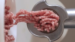 vertical video. mince meat with an electric meat grinder in the domestic kitchen, selective focus