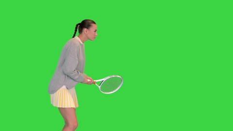 Medium shot. Side view. Girl with tennis racket imitating the game on a Green Screen, Chroma Key. Professional shot in 4K resolution. 068. You can use it e.g. in your medical, commercial video, busin