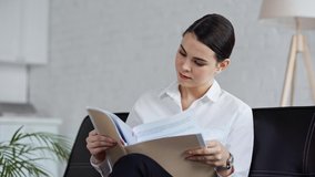 businesswoman looking at documents while holding folder