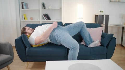 Plump male trying to zip up tight jeans, suffering from obesity, plus size