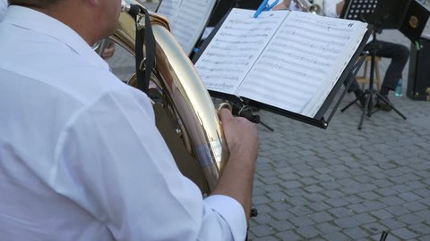 Musician is performing along the band with the Baritone horn, following the music sheets, somewhere outdoor. The baritone horn is a low-pitched brass instrument.   Video Stok