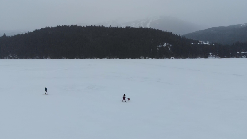 Aerial drone footage of cross country skier on frozen winter lake in Whistler, BC. 4K 24FPS.