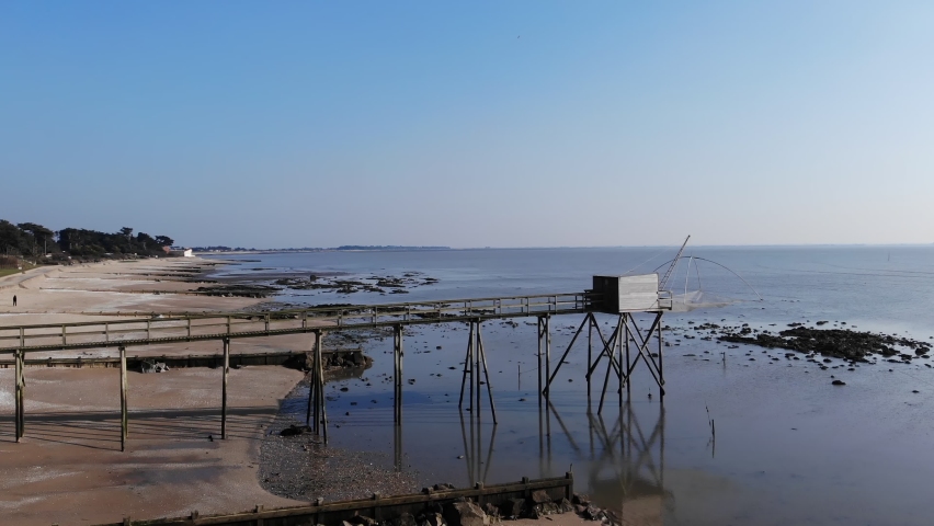 typical landscape fishing cabin: fishing huts net in carrelet. Typical old wooden fishing huts on stilts in the atlantic ocean. Aerial Beautiful drone shot of traditional french fisherman cabin