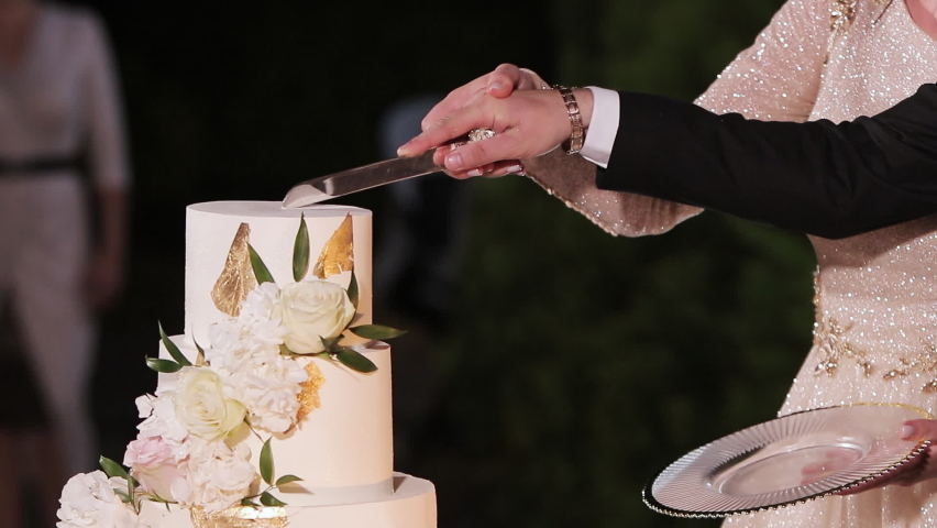 Cut the wedding cake. The bride and groom cut the wedding cake. Wedding cake with sparklers in several tiers. Detail of wedding cake cutting by newlyweds Royalty-Free Stock Footage #1069326868