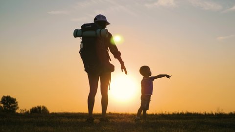 Happy family mom and son. Mother walks with little son holding hands at beautiful sunset. Mother holds her son by the hand. Helping hand. Teamwork and friendly family concept. Happy kid love for mom.