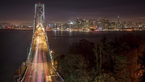 Time Lapse of traffic driving across the Bay Bridge in San Francisco. The buildings of San Francisco can be seen in the distance. Time Lapse.