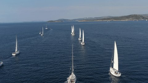 Ranks from yachts of participants of a regatta goes on a start point, is a sailing race at Croatia, reflection of sails on water, boat number aft boats