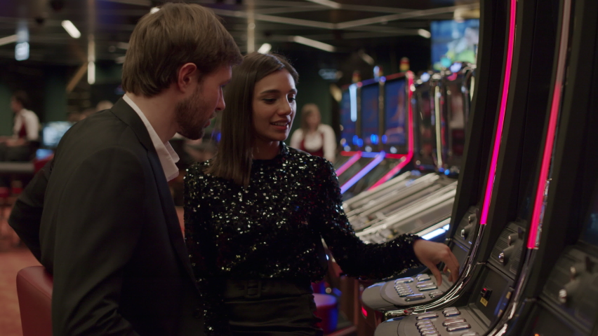 friends or couple enjoying playing the slot machine at the elite casino. Gambling, nightlife Royalty-Free Stock Footage #1069339369