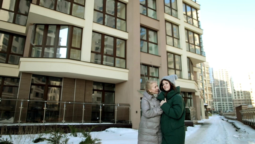Old woman and a girl stand on the street, in the city and communicate.