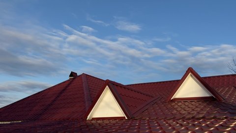 Red metal roof of house in sunny  day on background of blue sky.