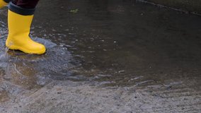 Run through puddle in yellow rubber boots and enjoy wet spring weather like little child. Video of legs without persons face. Enjoy and walk in rain.