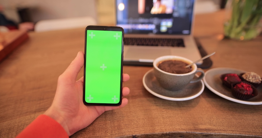 Green screen of smartphone chromakey in the male hand at the table in cafe, a Technology Video by AntGor