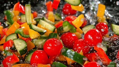 Super Slow Motion Shot of Colorful Vegetables Falling into Water on Black Background at 1000fps.