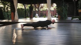 Yoga instructor in black protective mask and comfortable clothes performing exercises on mat at sun-drenched patio. Active lifestyle during pandemic - Powered by Shutterstock - Get 15% off with code: PIKWIZARD15