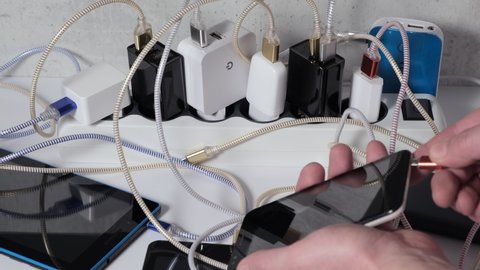 Smartphone Mobile Phone and tablets connected to Charging hub on the Table, micro usb   wires to chargers in sockets. Extension cord switch loaded with Charger adapters and cables for Recharge phones