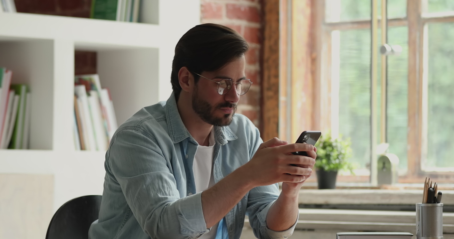 Man sit at desk using smartphone reading bad news unpleasant sms feels stressed and outraged, having problems complaints on cellphone device, wi-fi connection lost, slow internet, need repair concept Royalty-Free Stock Footage #1069356652