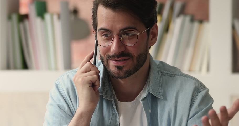 Close up view millennial man working in office holding wireless device talking to client having conversation on mobile phone, making solving business distantly using modern wireless technology concept Royalty-Free Stock Footage #1069356721