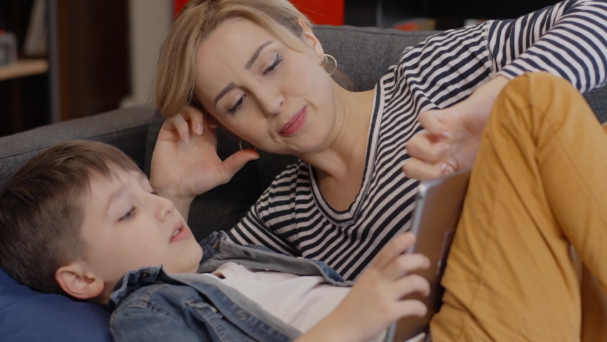 Happy mom and little boy using tablet with touchscreen together watching a video. Smiling mother and cute boy playing on digital tablet.Close up.