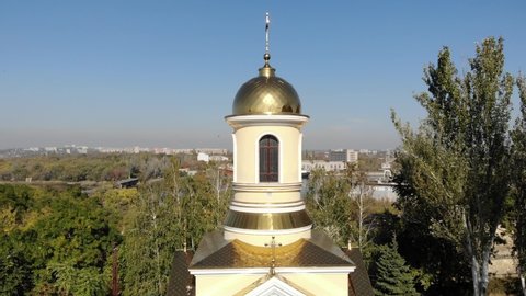 Orthodox church with golden domes near the river 4K video, the camera goes up near the church and overlooks the river with the ship, dron video of the church in a sunny day, Ukrainian church