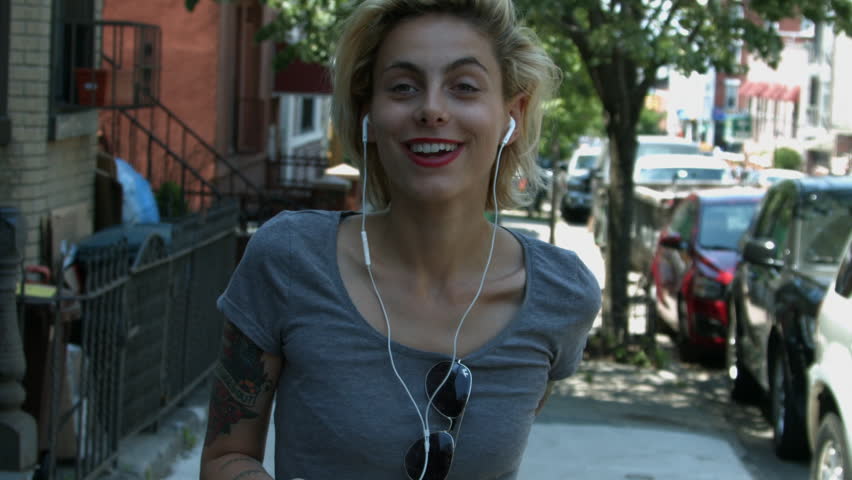 A young woman listening to music on headphones and rocking out outside in New York City