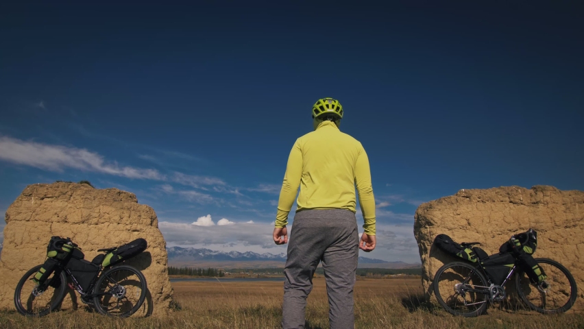 The man travel on mixed terrain cycle touring with bikepacking. The traveler journey with bicycle bags. Sport tourism bikepacking.