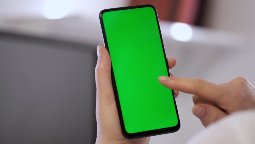 Handheld Camera: Point of View of Woman at Modern Room Sitting on a Chair Using Phone With Green Mock-up Screen Chroma Key Surfing Internet Watching Content Videos Blogs Tapping on Center Screen | Shutterstock HD Video #1069375657
