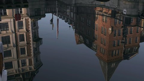 European Buildings and Bridge Reflected In Water in Canal Tilting Up to Empty Street